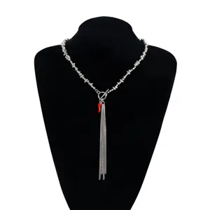Vue détaillée du collier argenté irrégulier avec pendentif piment rouge et pompons.