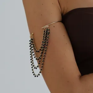 Golden upper arm cuff featuring multi-layer black beaded tassel design, closeup detail.