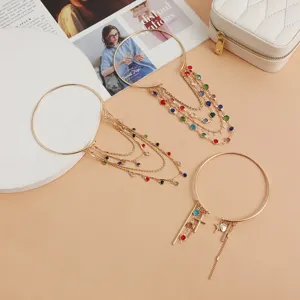 Detailed shot of trendy gold-tone arm cuffs with multi-strand chains and vibrant crystal stones.