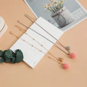 Detailed view of sweet raspberry pom-pom clavicle chain necklaces in gold and silver tones.
