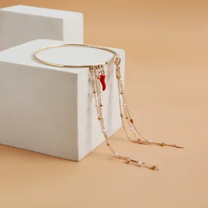 Detail shot of the vintage gold armlet featuring delicate tassel chains, pearls, and red chili.