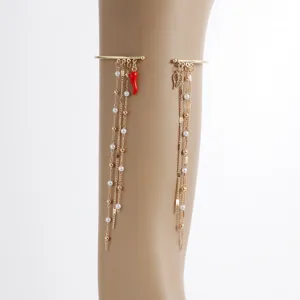 Gold metal arm cuff detailed view featuring delicate pearl chains, red chili and leaf pendants.