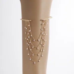 Gold-tone metal arm cuff bracelet with multi-layered tassel chains and pearl accents, stylish.