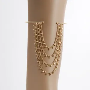 Gold tassel arm cuff detail, multi-layer chain bracelet, unique jewelry accessory.