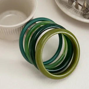 Green resin bangle detail close-up showing smooth curved surface and translucent gradient style.