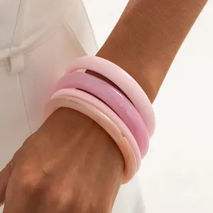 Detail shot of colorful marbled transparent resin bangles stack, smooth arc design, stylish jewelry.