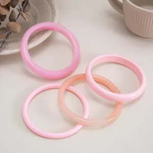 Close-up detail of stylish resin bangles set, featuring glossy pink and peach smooth surface rings.
