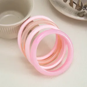 Close-up detail shot of colorful transparent resin bangles, smooth curved surface design.