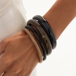Stacked resin bangles showcasing translucent textures and glossy finish on the wrist.