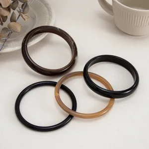 Detail shot of multi-color resin bangles, smooth surface design, minimalist fashion style.