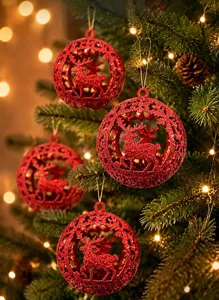 Detailed view of red glitter Christmas balls with hollow reindeer design hanging on a tree.