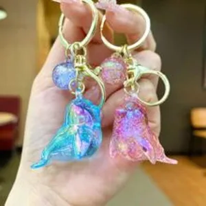Primer plano de llaveros de ballena con purpurina holográfica y herrajes dorados muy brillantes.