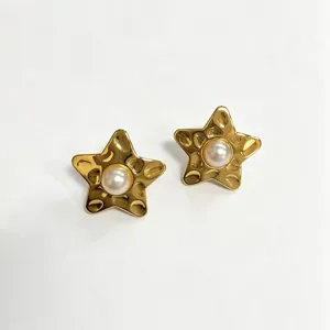 Gros plan détaillé sur les boucles d'oreilles étoile de mer dorées avec perle centrale.
