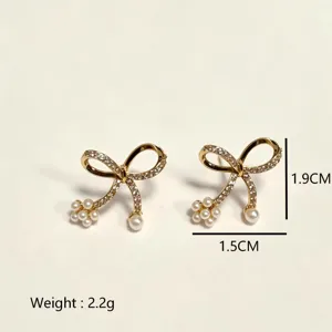 Elegant gold bowknot stud earrings featuring sparkling zircon and delicate pearl cluster accents.