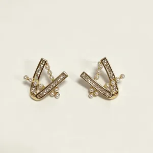 Gold geometric V-shaped stud earrings with sparkling zircon crystals and delicate pearls.
