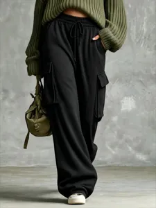 Detailed view of casual loose black cargo sweatpants with drawstring waist, styled with olive green.