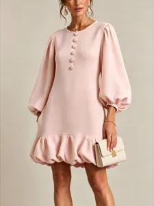 Close-up detail of light pink dress featuring floral buttons and voluminous lantern sleeves.