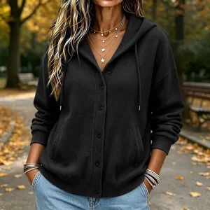 Detail shot of black knitted hooded cardigan with buttons and pockets in cozy autumn park setting.