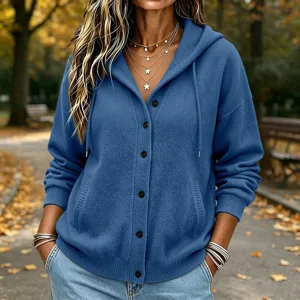 Blue knit hooded cardigan detail showing button closure, cozy texture and autumn outdoor scene.