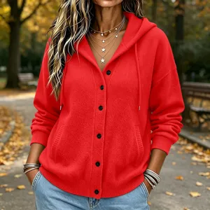 Detail shot of red knit hooded cardigan sweater with buttons and pockets in autumn park setting.