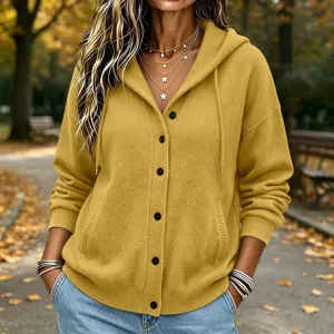 Detailed view of women's autumn yellow knitted hooded cardigan with buttons and pockets outdoors.