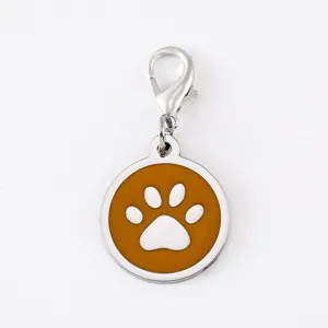 Close-up detail of stainless steel dog paw pendant charm with orange enamel and lobster clasp.