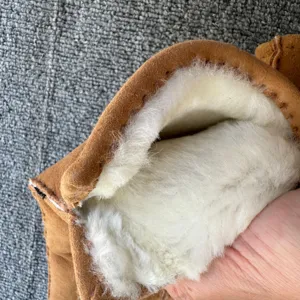 Thick shearling sheepskin glove interior lining detail, warm plush winter mitten close-up view.