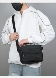 Detail view of the black canvas crossbody bag with multi-layer pockets and zipper closure.