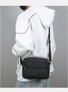 Men black canvas shoulder bag detail view, multi-pocket casual crossbody daily commuter messenger.