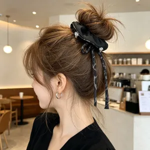 Coletero de tela negra con cintas elegantes y dijes metálicos para peinados de moño.