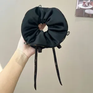 Vista detallada de coletero para el pelo de satén negro con bonitos lazos y anillos estilo vintage.