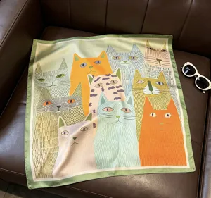 Gros plan d'un carré de soie en satin imprimé de chats artistiques, détail de foulard.