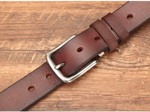Gedetailleerde close-up van donkerbruine echt lederen riem met metalen gesp op houten achtergrond