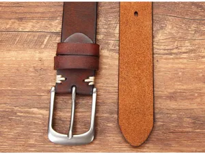 Vue détaillée de la ceinture en cuir de vachette marron avec boucle ardillon et coutures visibles.