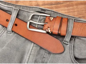 Gros plan détail de la boucle ardillon de ceinture en cuir véritable et jean texturé.