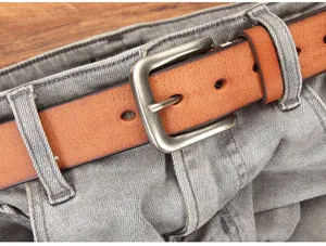 Gros plan détail d'une ceinture en cuir pour homme avec boucle métal classique sur jean gris.