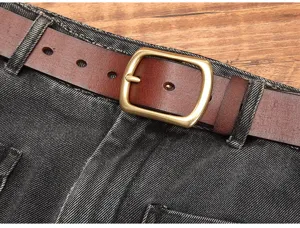 Cintura da uomo in vera pelle con fibbia ad ardiglione vintage su pantaloni in denim robusto.
