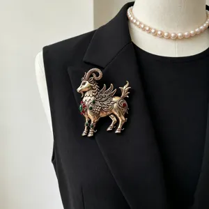 Detailed close-up of the vintage gold mythical ram brooch with emerald and ruby gemstone accents.