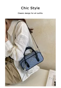 Blue denim quilted shoulder bag with black top handles and stylish metal chain charm.