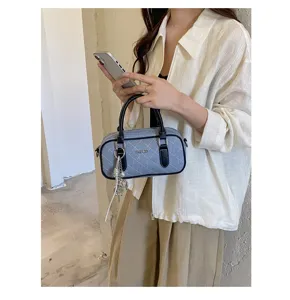 Detail view of the women quilted denim boston handbag, featuring black leather handles and charm.