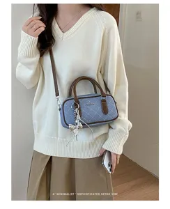 Detailed view of the blue denim quilted shoulder bag featuring brown leather trim and metal charms.
