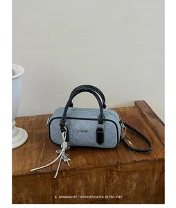 Detailed view of stylish quilted denim barrel bag with black handles and elegant retro vibe.