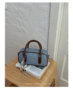 Close-up detail of stylish quilted denim pillow shoulder bag with brown leather handles.
