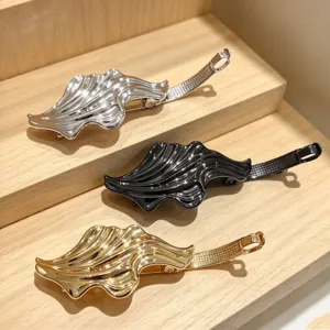 Detailed view of three stylish metallic hair clips in silver, black, and gold on wooden shelf.