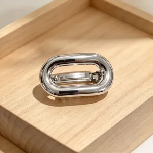 Scatto di dettaglio dell'elegante molletta per capelli ovale geometrica argentata, design moderno.