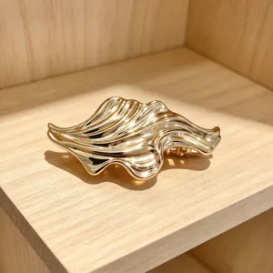 Detailed shot of a trendy irregular wavy gold metal hair claw clip, perfect for elegant updo styles.