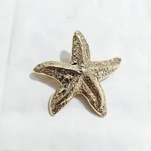 Gold starfish hair clip detail shot, elegant metal barrette showing delicate textured surface.