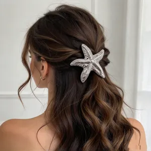 Detailed view of an elegant silver starfish metal hair clip worn on brown wavy hair.