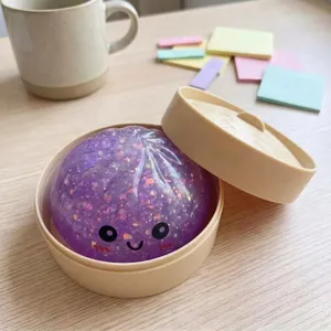 Giocattolo antistress viola glitterato con faccia carina in mini cestino vaporiera.