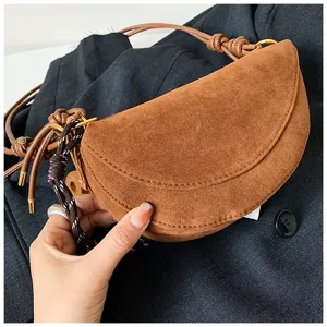 Close-up detail shot of the brown suede half-moon shoulder bag showcasing texture and design.